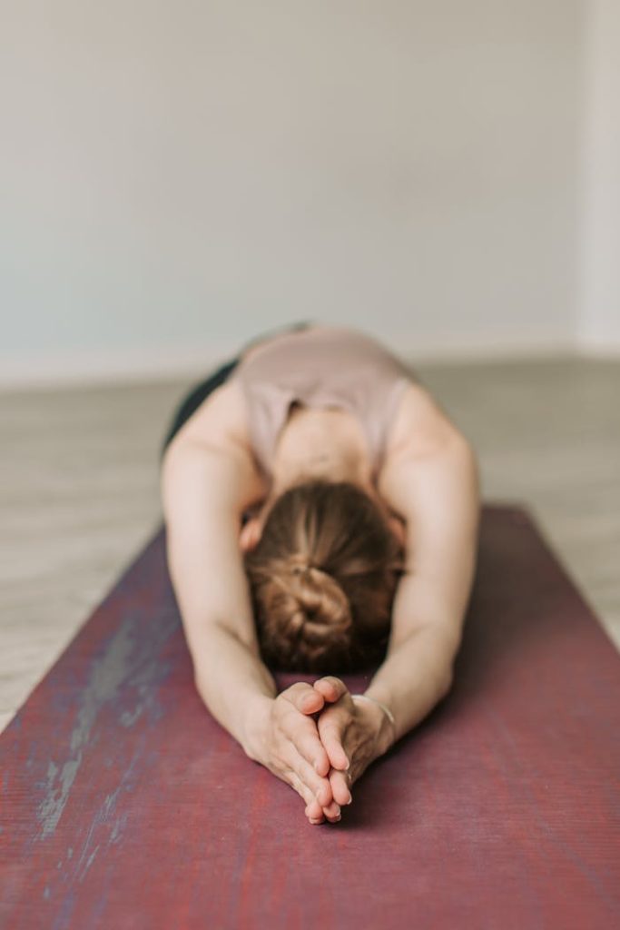 A woman stretches in Childs Pose during a yoga session, promoting wellness and relaxation.